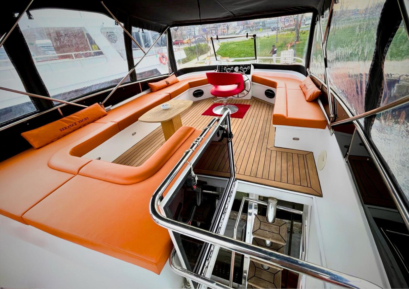 Spacious upper deck lounge with orange seating and teak floor